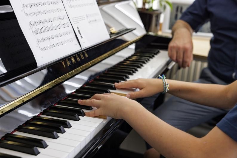 Die Hände eines Musikschulers am Klavier beim Unterricht