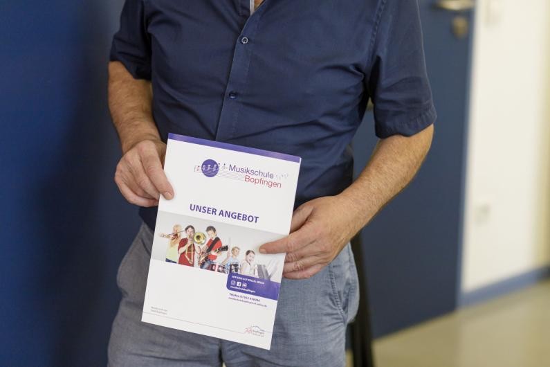 Flyer Unser Angebot Eine Person hält den Flyer der Musikschule "Unser Angebot" in den Händen