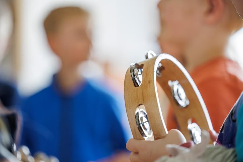 Drei spielende Mädchen und eine Lehrerin mit Trommeln bei der musikalischen Früherziehung